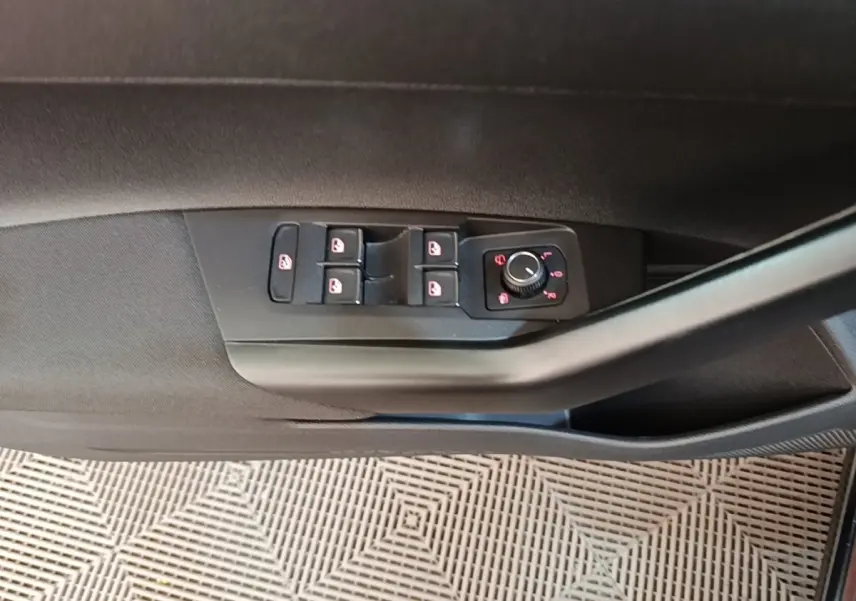 Vue rapprochée de la commande des vitres et rétroviseurs sur la porte côté conducteur d'une Volkswagen Polo noire.