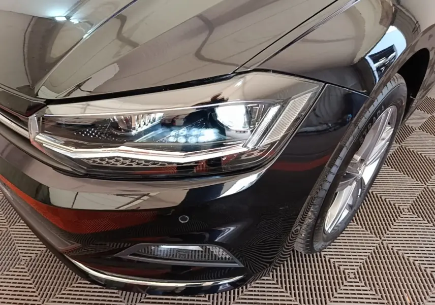 Gros plan sur le phare avant droit d'une Volkswagen Polo noire 2020 avec jante alliage et antibrouillard intégré.