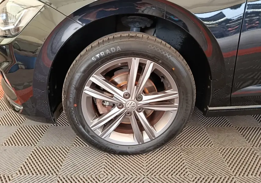 Gros plan sur la roue avant gauche noire d'une Volkswagen Polo 1.0 TSI 115 DSG7 Carat avec jante alliage argentée.