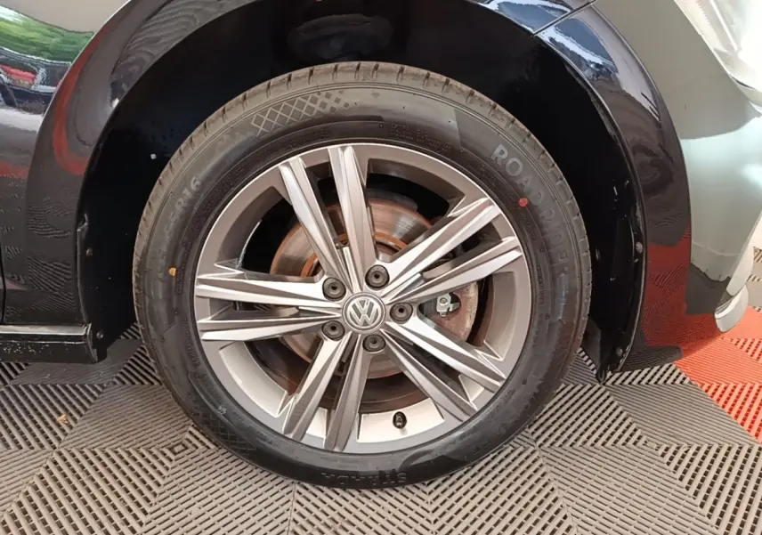 Gros plan sur la roue avant droite d’une Volkswagen Polo noire, mettant en valeur la jante alliage à cinq doubles branches.