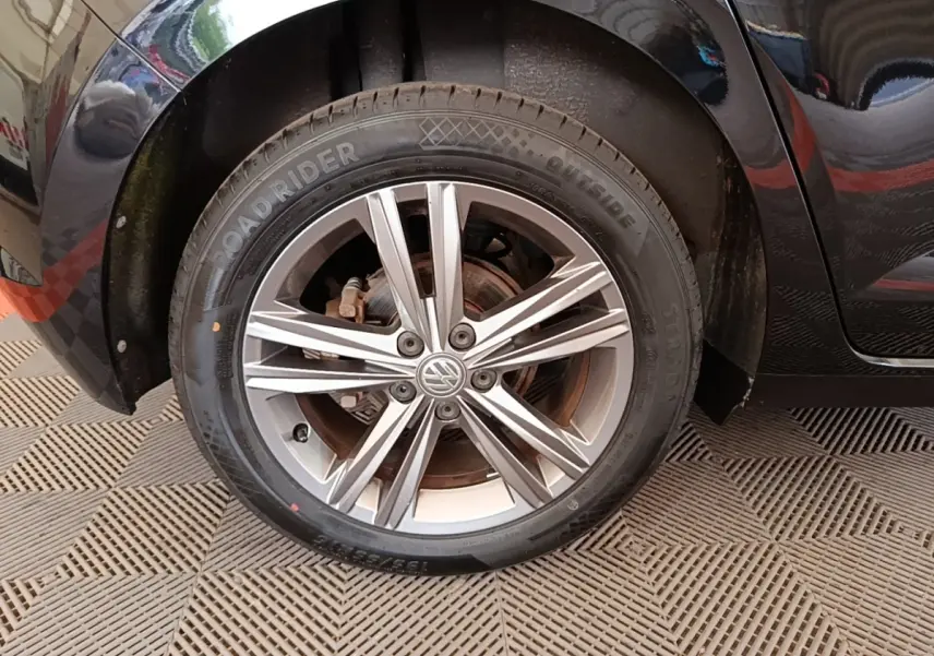 Gros plan sur la roue avant droite d'une Volkswagen Polo noire, mettant en valeur la jante alliage à plusieurs branches.