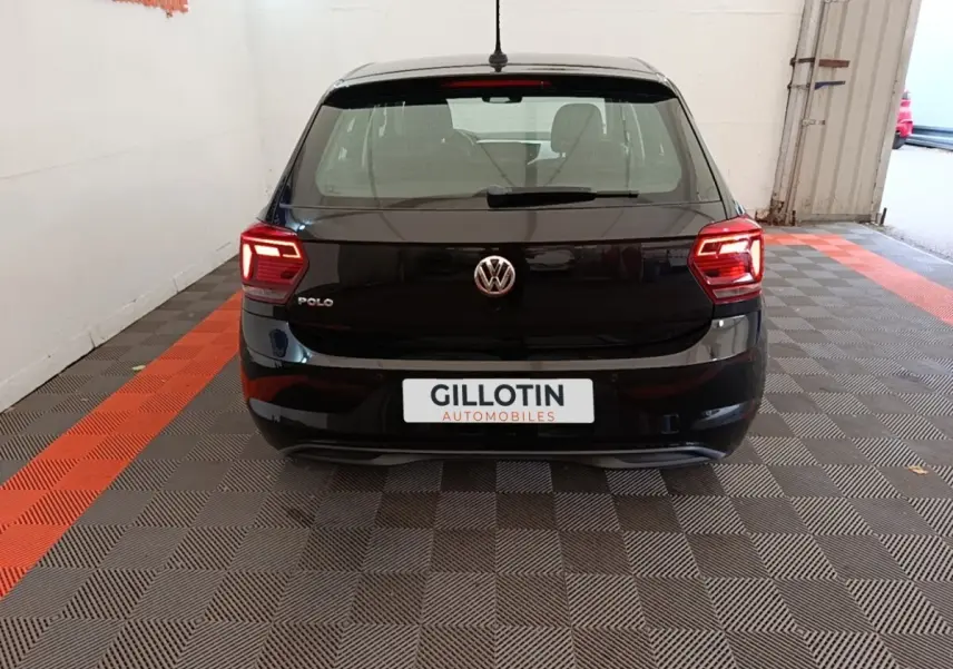 Vue arrière d'une Volkswagen Polo noire 2020 avec feux LED allumés, stationnée sur sol à damier gris et rouge.