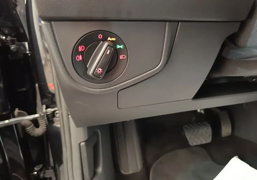 Gros plan sur le bouton de commande des phares dans l'habitacle noir d'une Volkswagen Polo 2020.