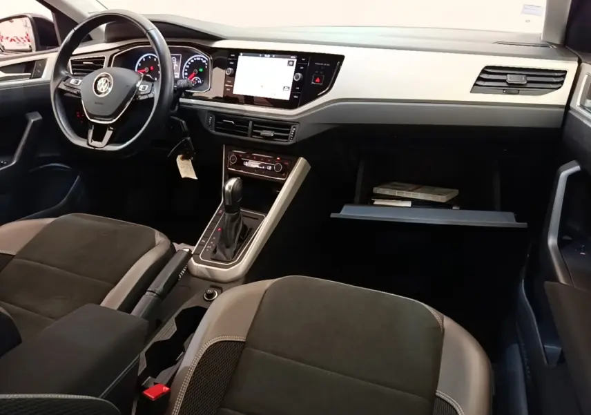 Vue intérieure avant droite de la Volkswagen Polo noire 2020, tableau de bord clair avec écran tactile et volant multifonctions.