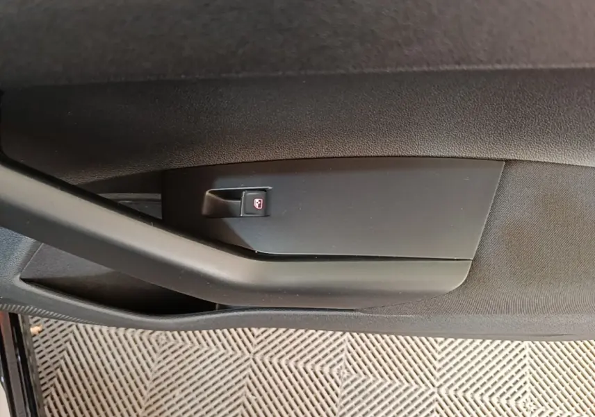 Détail de la poignée intérieure noire de la porte côté gauche d'une Volkswagen Polo noire vue de près.