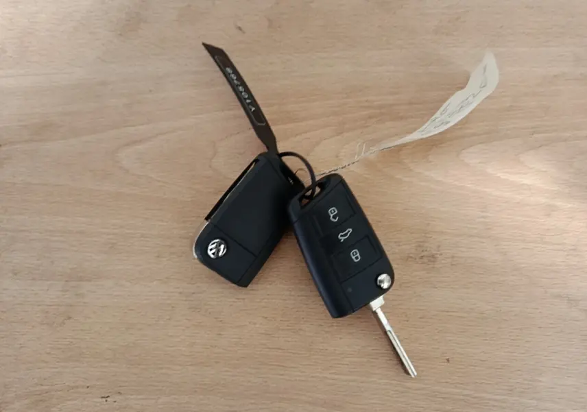 Clés noires Volkswagen Polo 1.0 TSI 115 DSG7 Carat posées sur une surface en bois clair.