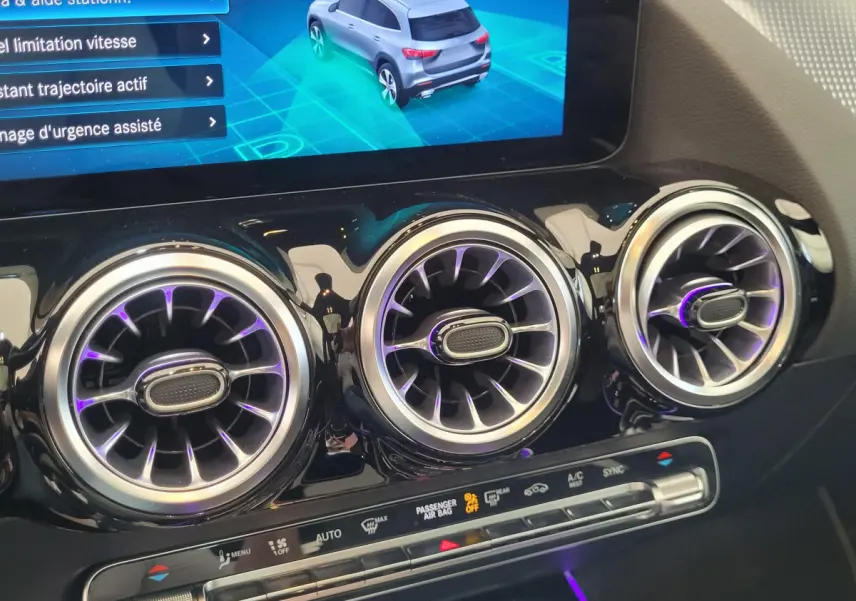 Gros plan sur les aérateurs ronds chromés et l'écran tactile du tableau de bord d'une Mercedes GLA 200 D bleu 2022