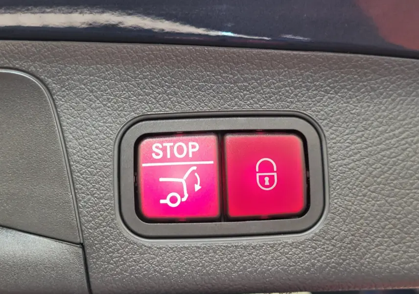 Gros plan sur les boutons rouges de fermeture et arrêt du hayon du Mercedes GLA 200 D bleu, version 2022.