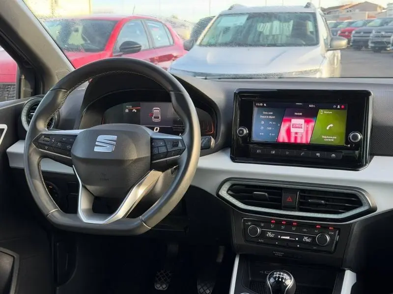 Vue intérieure du poste de conduite de la SEAT Ibiza 2025, avec volant multifonction et écran tactile central allumé.