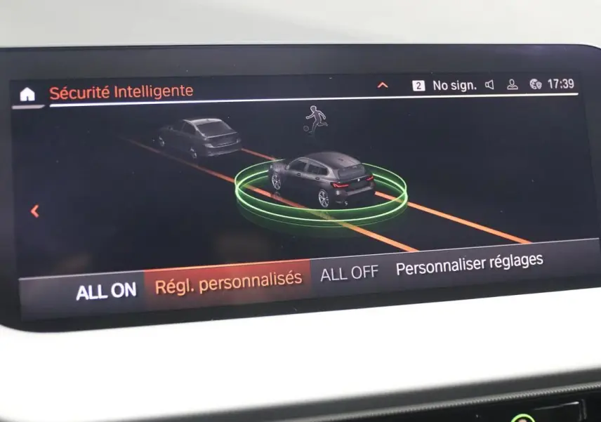 Écran de la BMW Série 1 noire 116d 2023 montrant l'interface de sécurité intelligente avec vue 3D du véhicule en circulation.