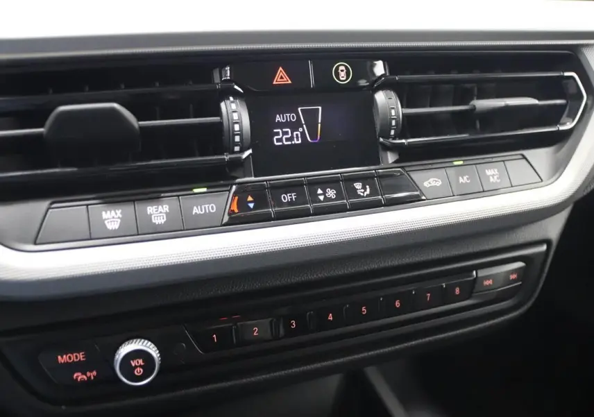Gros plan sur la console centrale de la BMW Série 1 116d noire, affichant la climatisation automatique à 22°C.