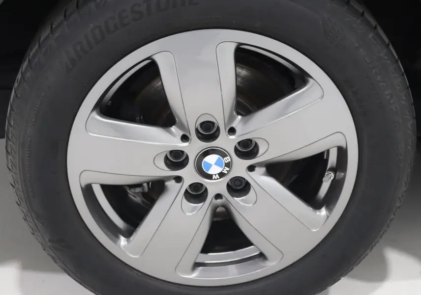 Gros plan sur la jante alliage argentée avec logo BMW au centre d’une BMW Série 1 noire.