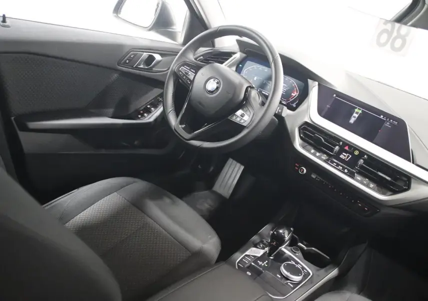 Vue intérieure côté conducteur de la BMW Série 1 116d noire, avec tableau de bord digital et écran central GPS.