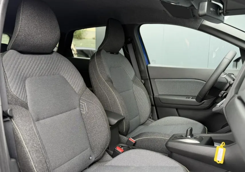 Vue intérieure côté droit du Renault Captur 2026, sièges tissu gris avec console centrale et volant visible.