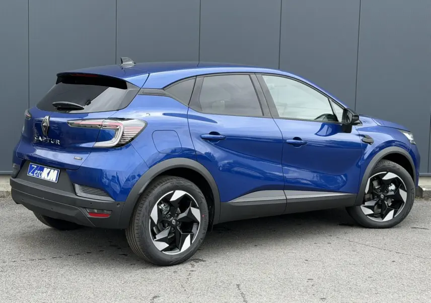 Vue 3/4 arrière droite du Renault Captur 2026 en Bleu Iron avec jantes aluminium 18 pouces et antenne requin noire.
