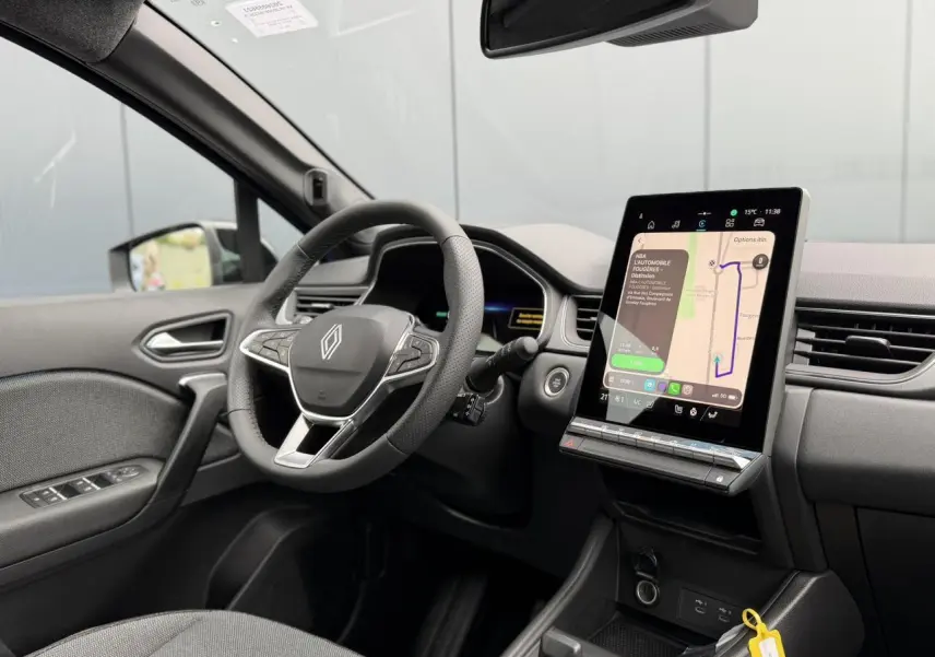 Vue intérieure côté conducteur du Renault Captur 2026, volant multifonction et écran tactile vertical affichant la navigation.