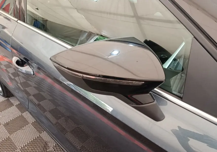 Gros plan sur le rétroviseur droit gris clair d’un SEAT Arona 2019, avec poignée de porte visible en arrière-plan.