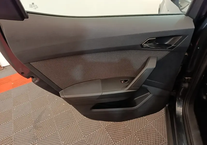 Détail de la porte intérieure côté droit d'une SEAT Arona gris clair, avec poignée et commande de vitre.