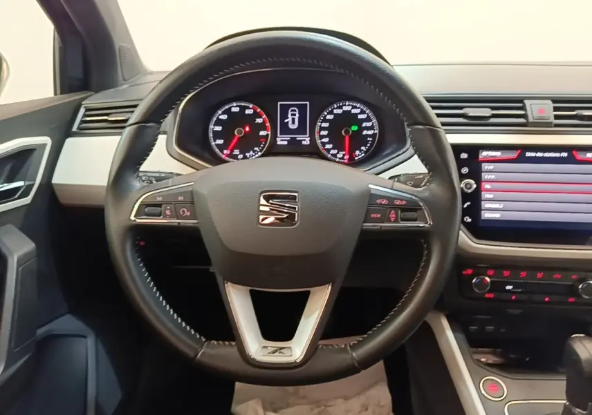 Vue centrée sur le volant en cuir noir d'une SEAT Arona 2019, avec tableau de bord et écran tactile visibles.