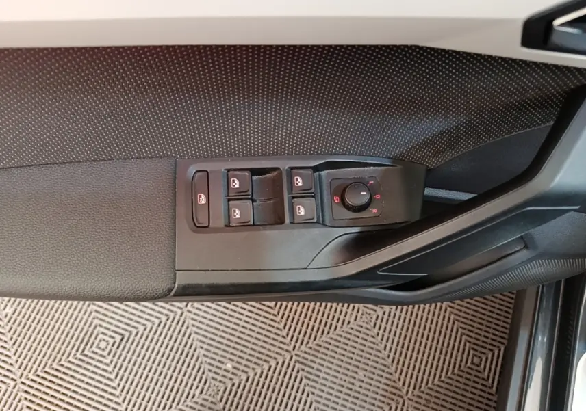 Gros plan sur la commande des vitres et rétroviseurs côté conducteur d’une SEAT Arona gris clair, intérieur noir.