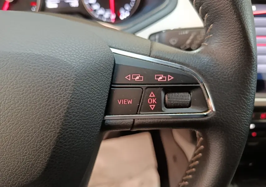 Gros plan sur les commandes à droite du volant cuir du SEAT Arona gris clair, avec tableau de bord numérique en arrière-plan.