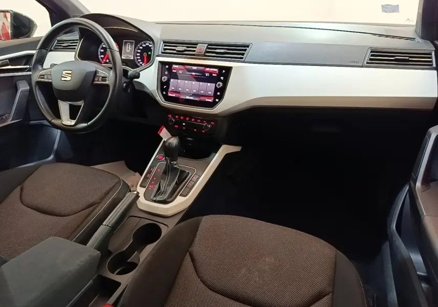 Vue intérieure avant droite du tableau de bord et console centrale du SEAT Arona gris clair avec écran tactile et volant multifonctions.