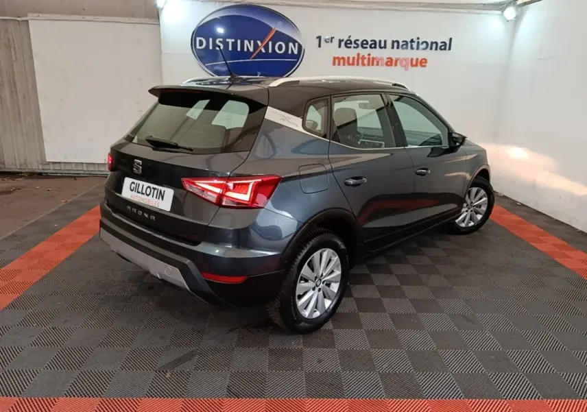 Vue 3/4 arrière droite d'un SEAT Arona gris clair 2019 dans un showroom avec éclairage intérieur.