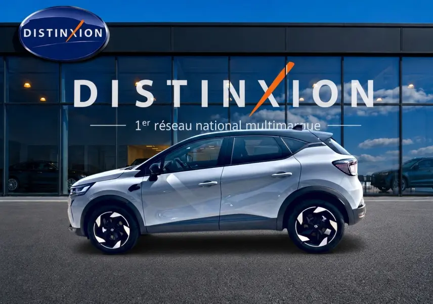 Profil latéral gauche du Renault Captur 1.2 TCe 115 Techno 2026 en couleur Rafale avec toit noir devant une vitrine Distinxion.