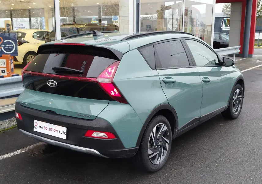 Vue 3/4 arrière droite d’un Hyundai Bayon 2022 vert Elemental Brass Metal avec feux arrière LED et jantes alliage.