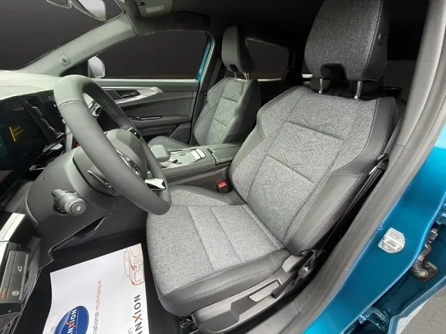 Vue intérieure côté conducteur du Renault Austral 2026 bleu, sièges tissu gris avec surpiqûres et volant cuir multifonctions.