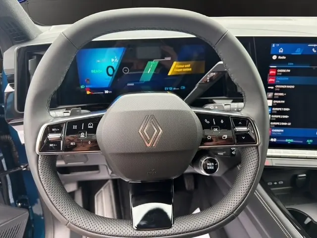 Vue rapprochée du volant cuir multifonctions du Renault Austral bleu 2026, avec tableau de bord numérique et écran tactile visible.