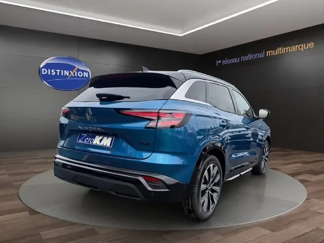 Vue 3/4 arrière droite du Renault Austral bleu bi-ton avec hayon motorisé et jantes RS dans un showroom.