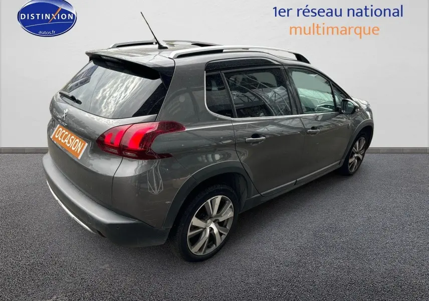 Vue 3/4 arrière droite du Peugeot 2008 gris platinium avec barres de toit et jantes alliage 17 pouces.