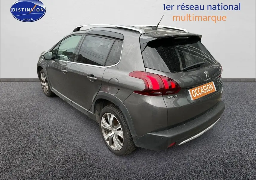 Vue 3/4 arrière gauche d'un Peugeot 2008 gris platinium avec barres de toit et jantes alliage 17 pouces.