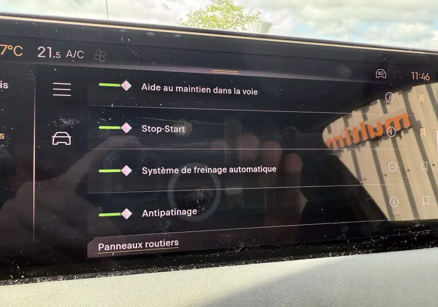 Écran tactile intérieur du DS3 2024 affichant les aides à la conduite et la climatisation, avec reflet extérieur.
