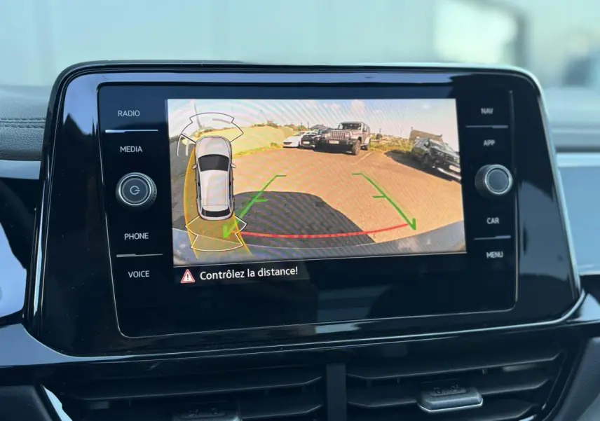 Écran tactile intérieur affichant la caméra de recul du Volkswagen T-Roc gris Indium avec alertes de distance.