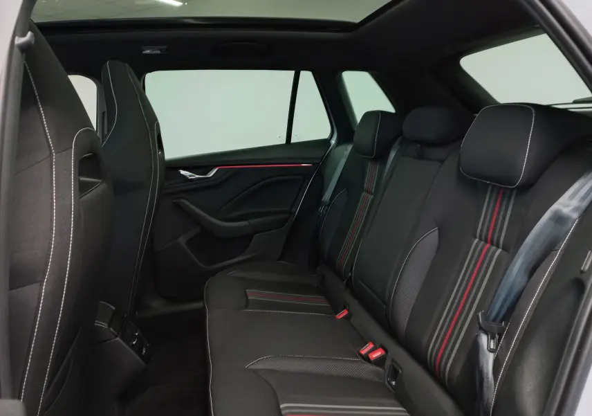 Vue intérieure arrière côté gauche du Skoda Kamiq 1.5 TSI Monte-Carlo 2025 avec sièges noirs à surpiqûres rouges.