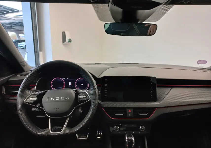 Intérieur du Skoda Kamiq 2025 vu de face, tableau de bord noir avec éclairage rouge et volant multifonction marqué SKODA.