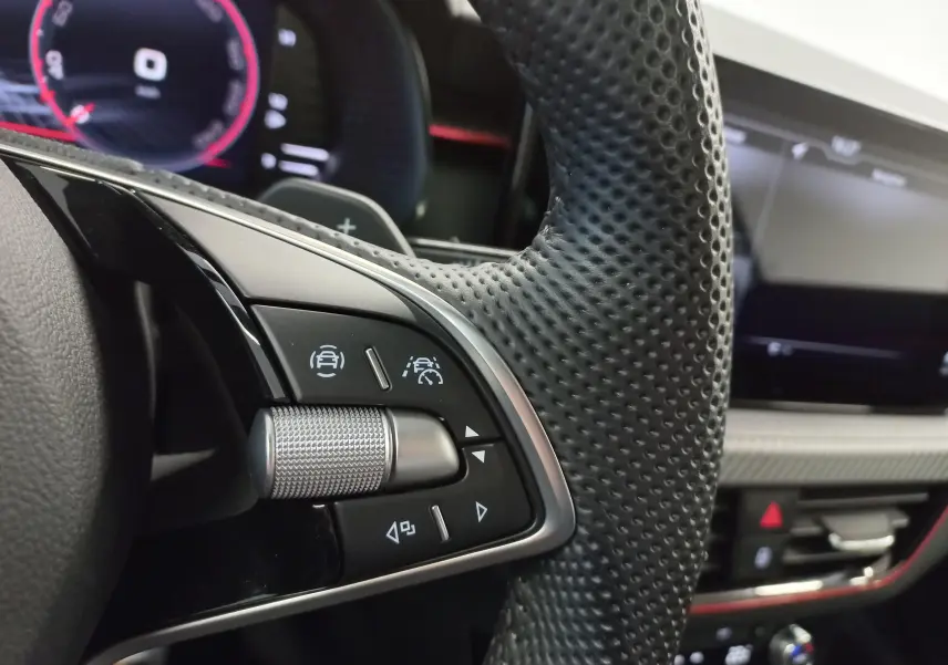 Gros plan sur les commandes du volant perforé du Skoda Kamiq 2025, tableau de bord numérique en arrière-plan.