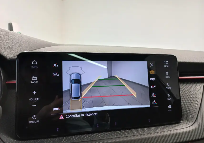 Écran tactile intérieur montrant la caméra de recul du Skoda Kamiq blanc Lune en vue arrière avec guidage dynamique.