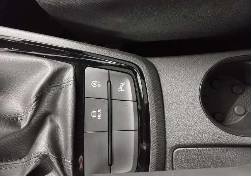 Gros plan sur la console centrale du Skoda Kamiq blanc, montrant les boutons de mode, arrêt auto et aide au stationnement.