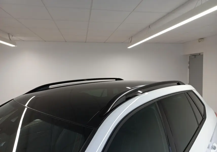Toit panoramique noir et barres de toit noires sur le côté droit d’un Skoda Kamiq Blanc Lune 2025.