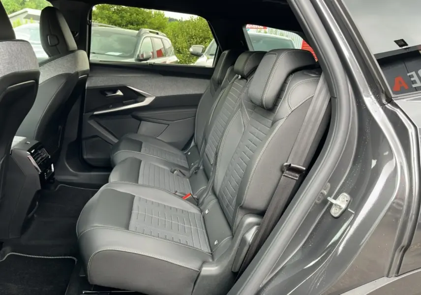 Vue côté droit sur la banquette arrière en cuir et tissu gris du Peugeot 5008 Hybrid 145 GT 2025 avec porte ouverte.
