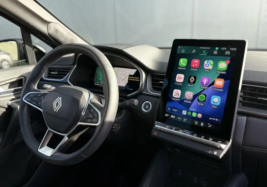 Vue intérieure côté conducteur du Renault Symbioz 2025, avec volant noir et grand écran tactile vertical affichant Apple Carplay.