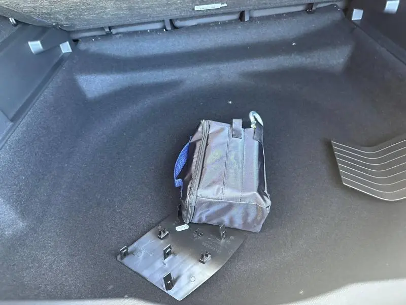 Coffre ouvert d’un Citroën C5 Aircross gris Platinium, vue plongeante sur espace vide avec trousse noire.