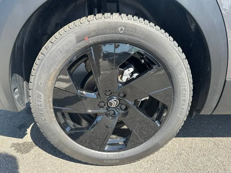 Gros plan sur la roue avant gauche du Citroën C5 Aircross gris Platinium, jante noire brillante avec logo Citroën central.