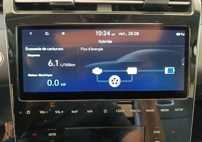 Écran tactile central affichant la consommation hybride et le flux d'énergie du Hyundai Tucson blanc, vue intérieure rapprochée.