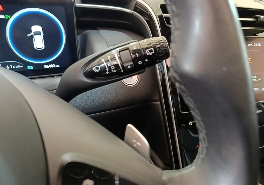 Gros plan sur le combiné d'instruments et le commodo d'essuie-glace du Hyundai Tucson blanc, intérieur noir.