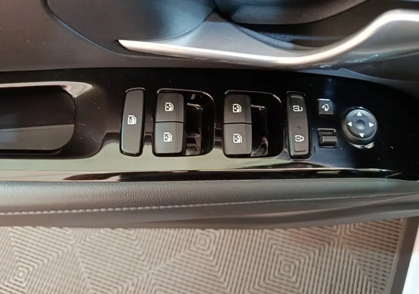 Gros plan sur les commandes de lève-vitres et rétroviseurs côté conducteur du Hyundai Tucson blanc 1.6 Hybrid 230 Executive 2022.