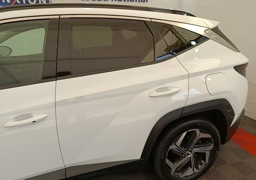 Vue latérale droite du Hyundai Tucson blanc 2022, mettant en valeur les vitres teintées et les jantes alliage distinctives.